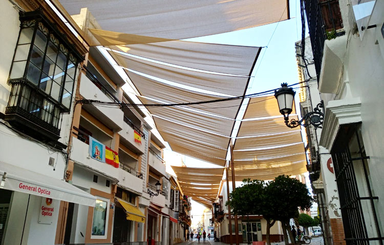 La utrerana calle Virgen de Consolación estrena sombra con el montaje de los nuevos toldos